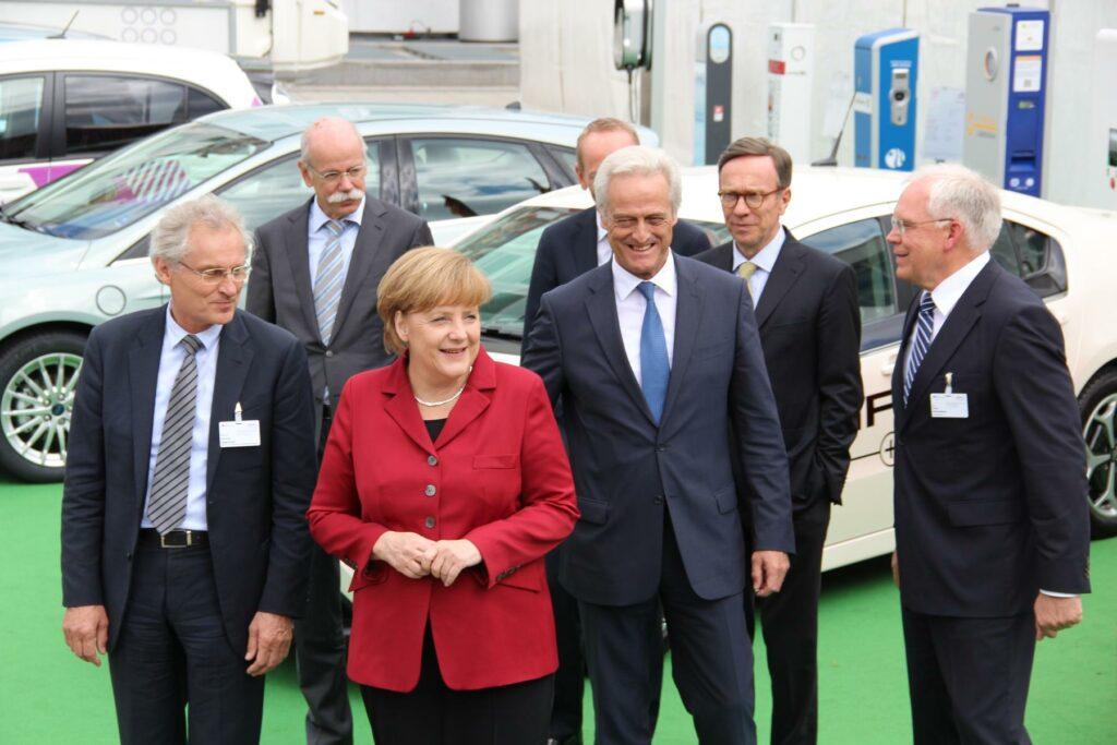 a group of men and women standing in front of a car - File:Angela Merkel and Automotive Managers.JPG