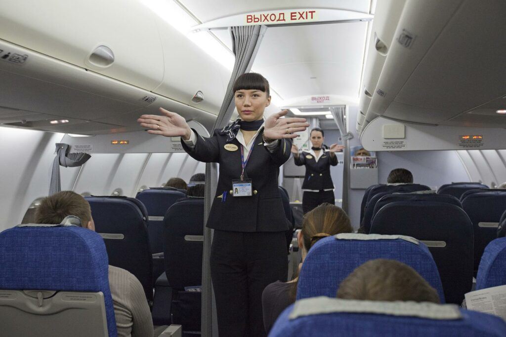 a woman in a plane - Flight attendants performing a pre-flight safety demonstration on an Aeroflot S